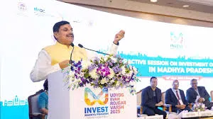 A speaker in white kurta and yellow Nehru jacket addresses the audience at the "Invest Madhya Pradesh 2025" investors summit, with the backdrop highlighting an interactive session on investment opportunities in Madhya Pradesh.