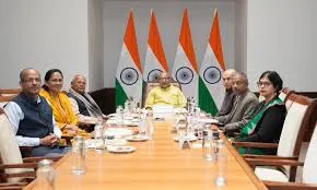 Vice-President of India Shri C. P. Radhakrishnan seated at a conference table with Union MSME Minister Shri Jitan Ram Manjhi, Minister of State Sushri Shobha Karandlaje and senior officials during a briefing at Parliament House, with Indian national flags and Ashoka Pillar emblem in the background.