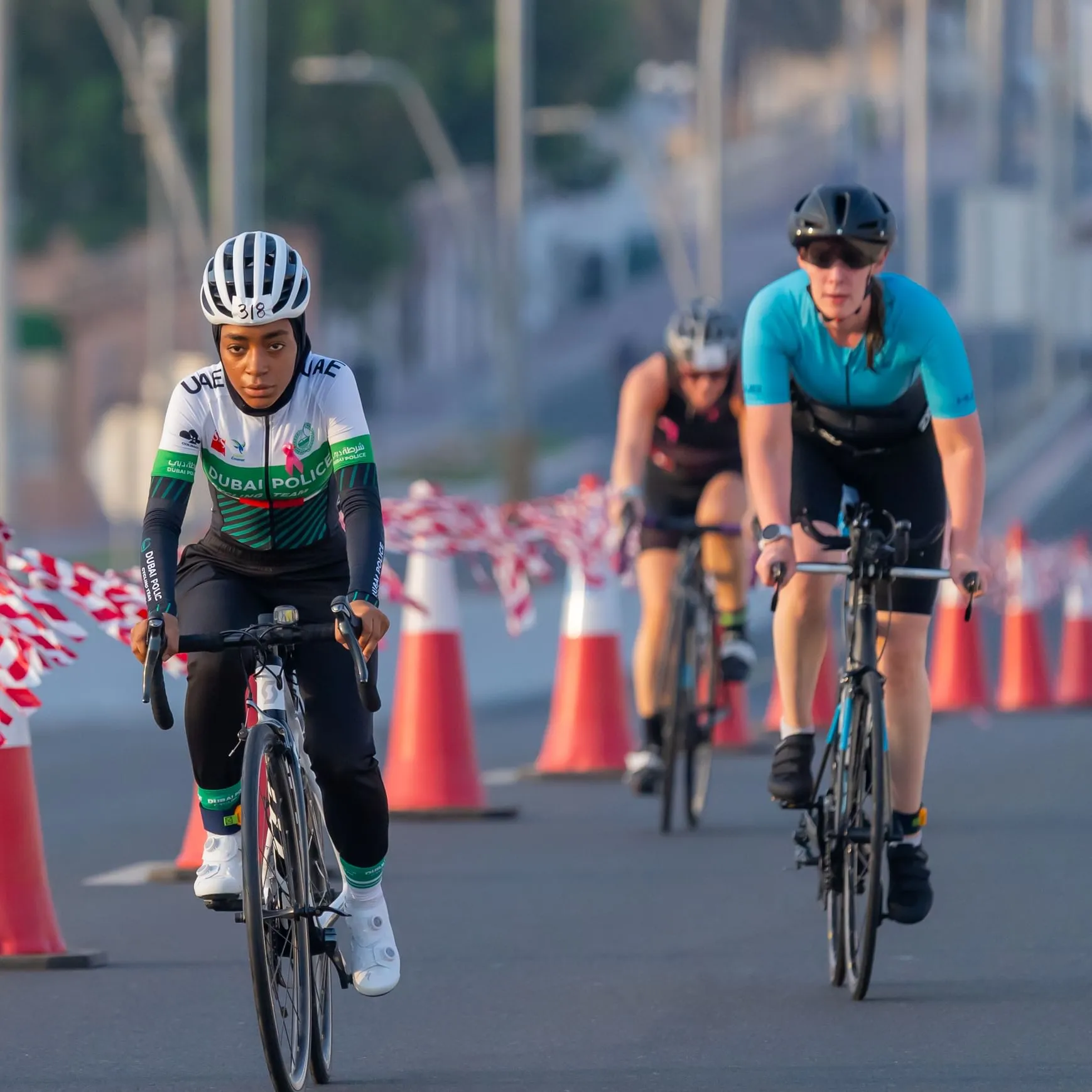 Female cyclist wearing a Dubai Police triathlon suit and race number 318 leads the cycling segment of the 2025 World Triathlon Women’s Cup at Dubai Islands, UAE.