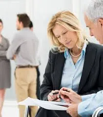 Sara Halton, Non-Executive Director of the Crown Commercial Service, reviews documents on her smartphone while holding papers in a professional business setting.
